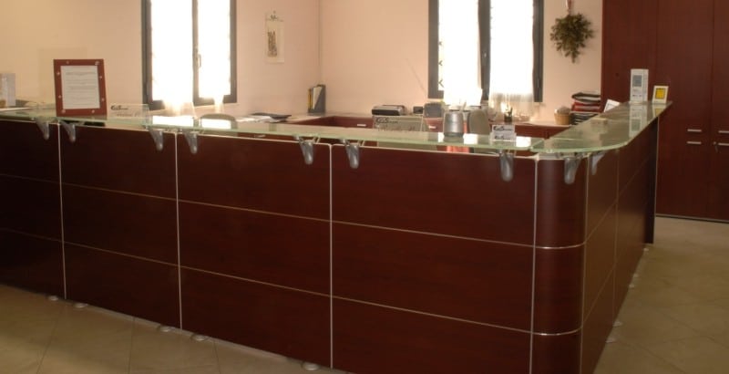 Banco reception in legno con piano in vetro.