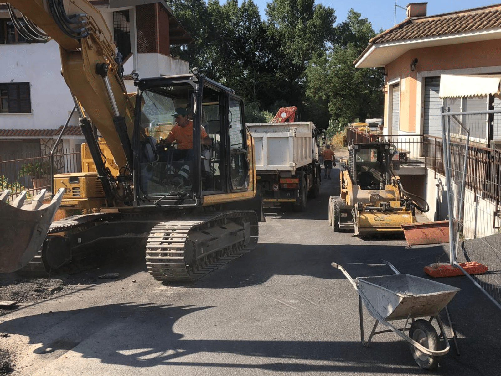 Cantiere stradale con escavatore, camion e attrezzature edili.