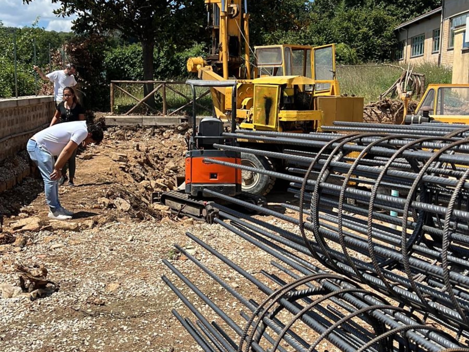 Persone e macchinari in un cantiere edile all'aperto.