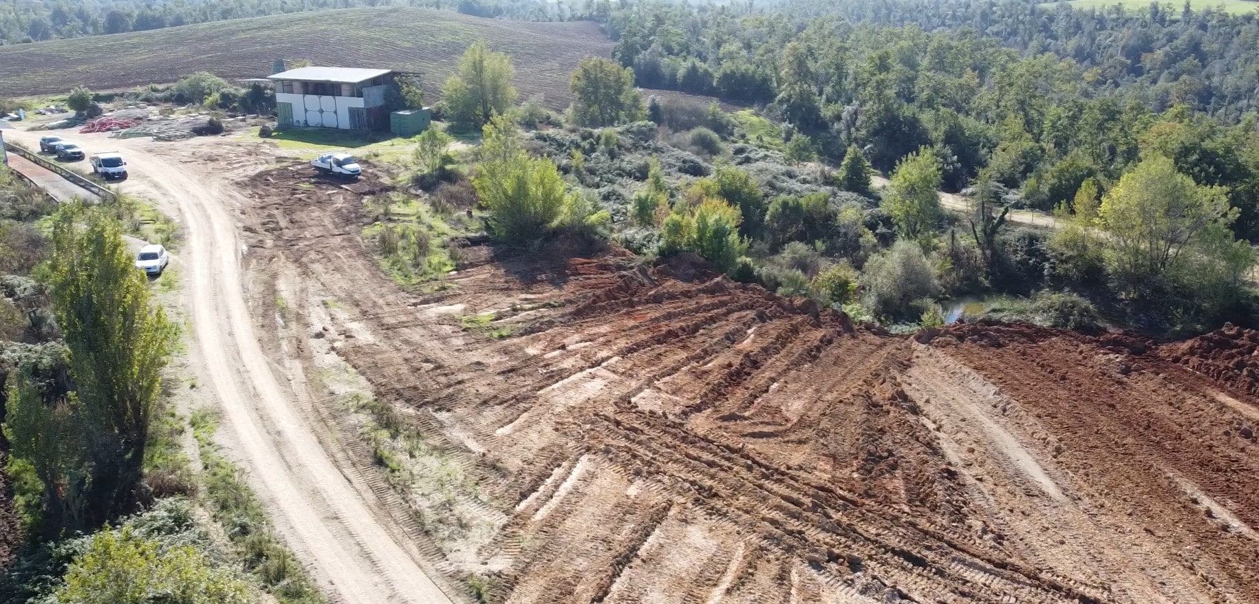 Terreno con strada sterrata e vegetazione circostante.