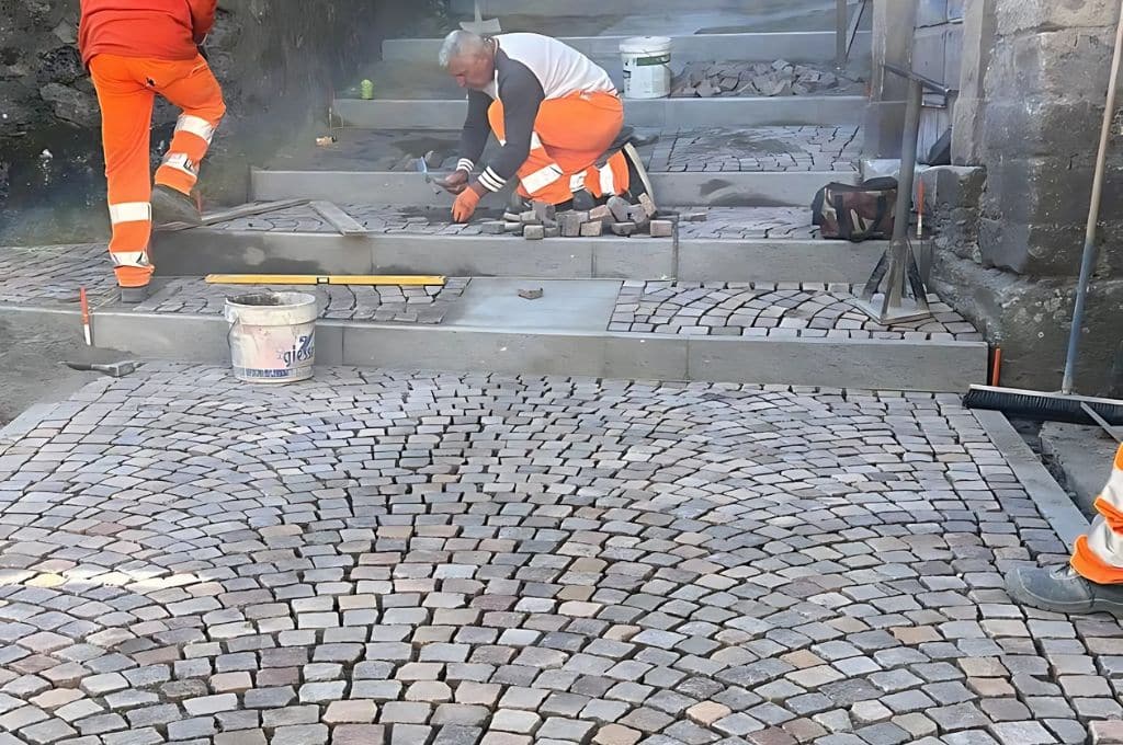 Operai posano pavimentazione in pietra su una scalinata.